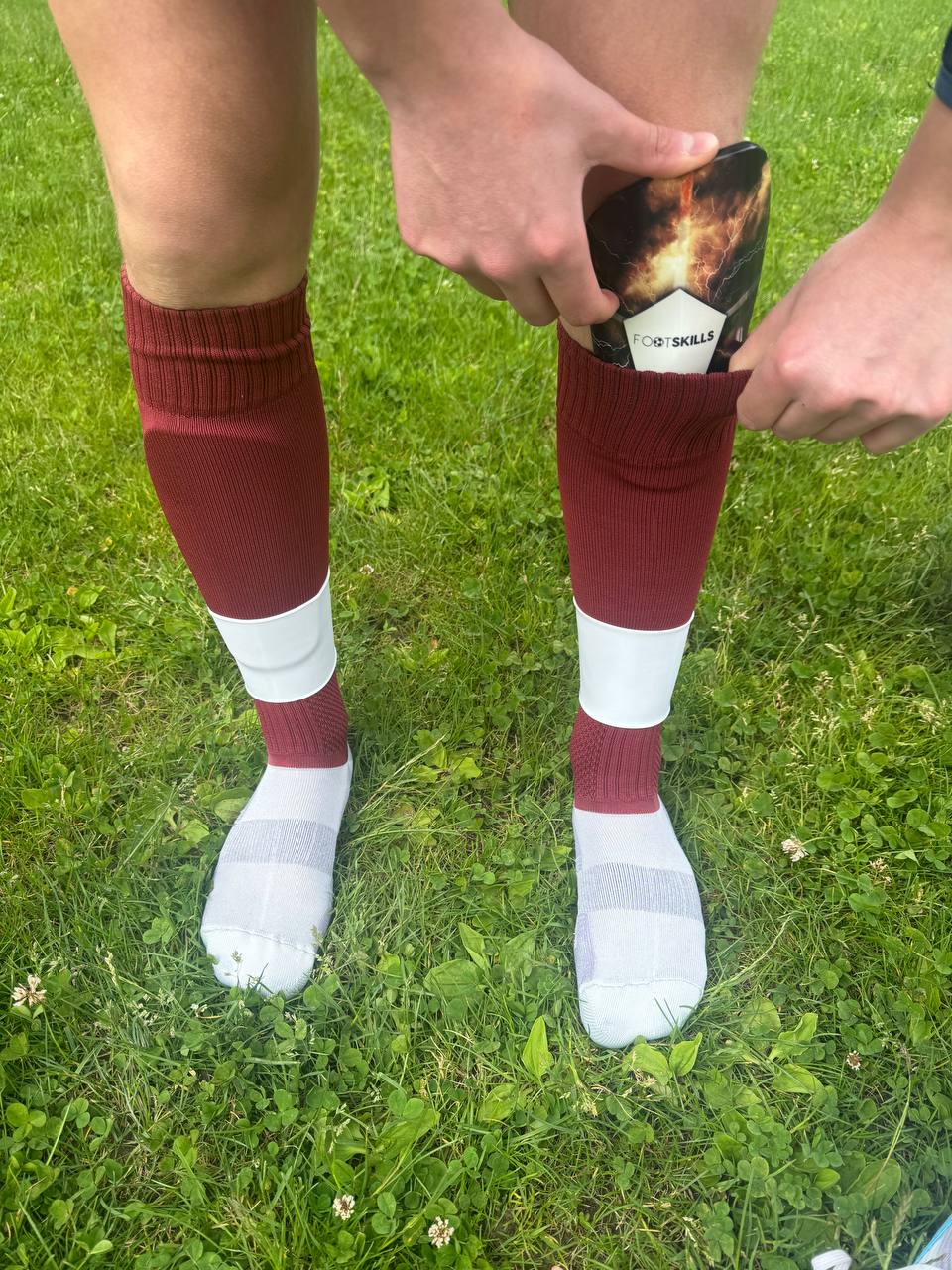 Calciatore che indossa parastinchi Footskills sotto i calzettoni rossi durante una sessione di allenamento.