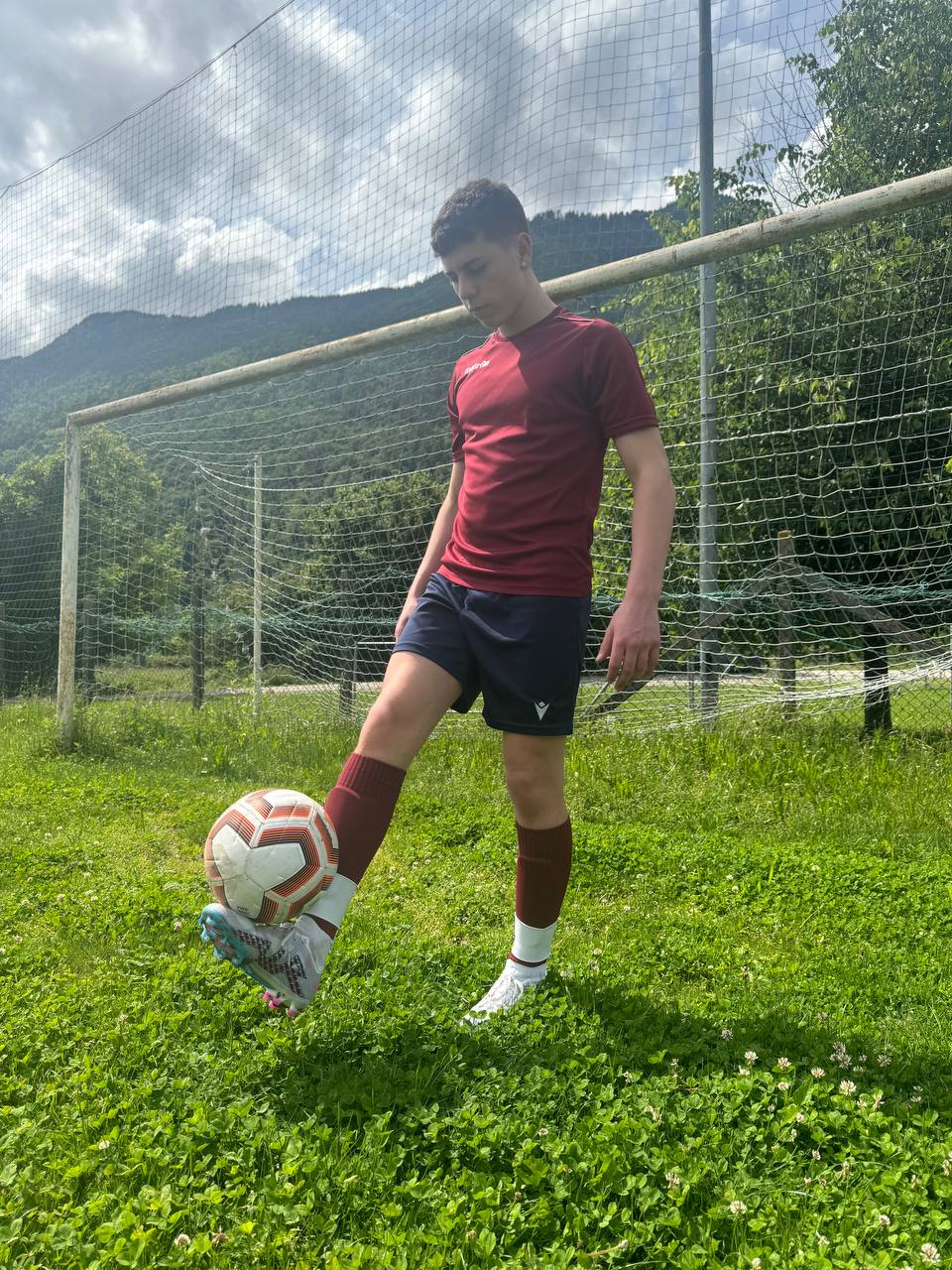 Giovane calciatore durante una sessione di allenamento con un pallone, indossando l'abbigliamento sportivo Footskills.