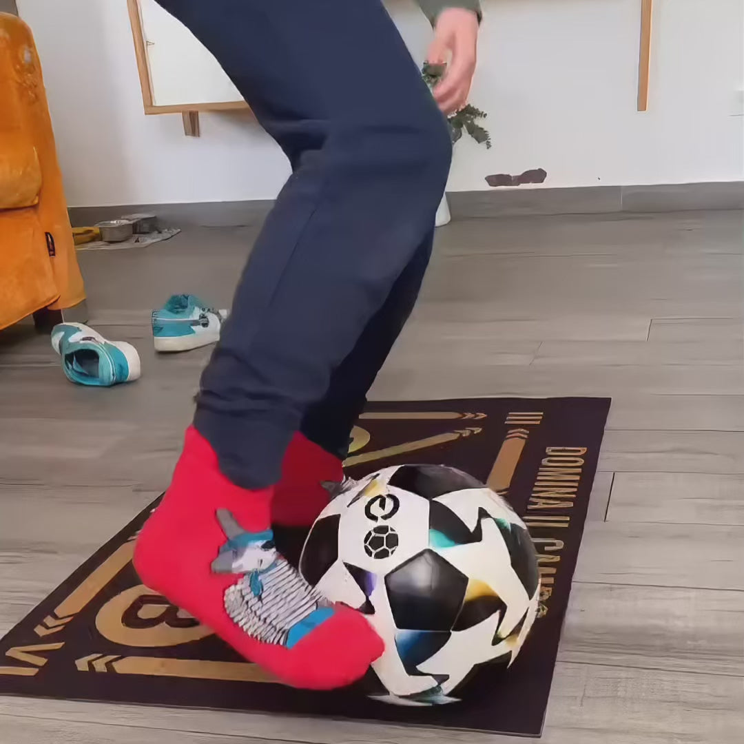A boy trains on the FootSkills mat, following exercises from the video course created by the world champion. He is wearing red and blue socks.